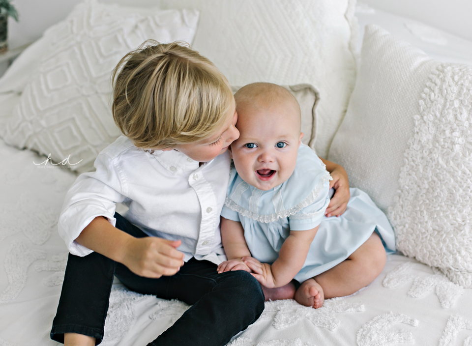 Big brother kissing little brother sitting on bed Jackson area photography