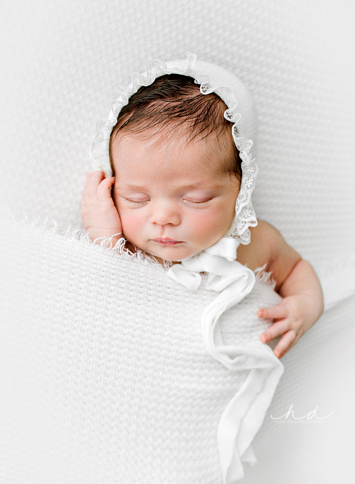 newborn in white lace bonnet natural pose