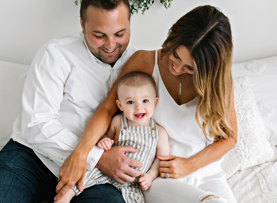 minimalist one year old family sitting on bed