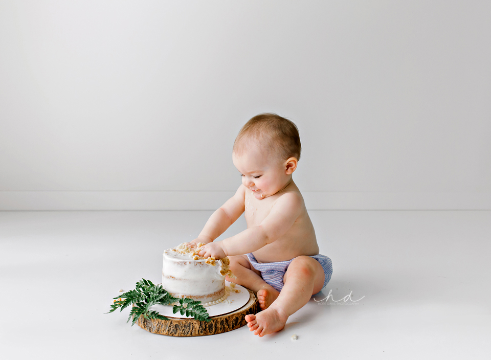 white cake smash with greenery on wood