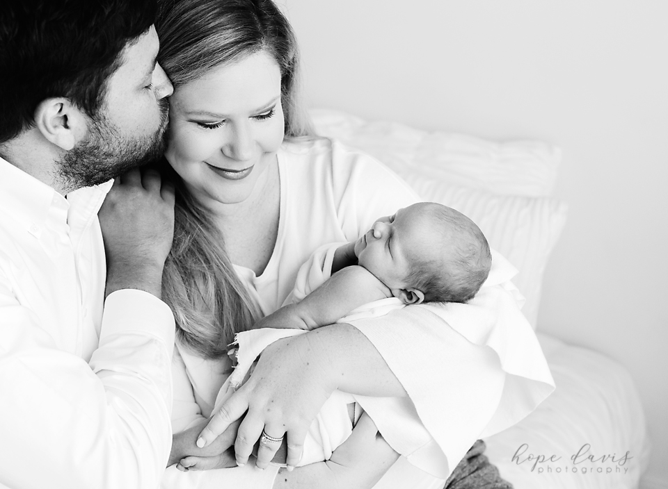 brandon ms best newborn photographer dad kissing mom while holding baby