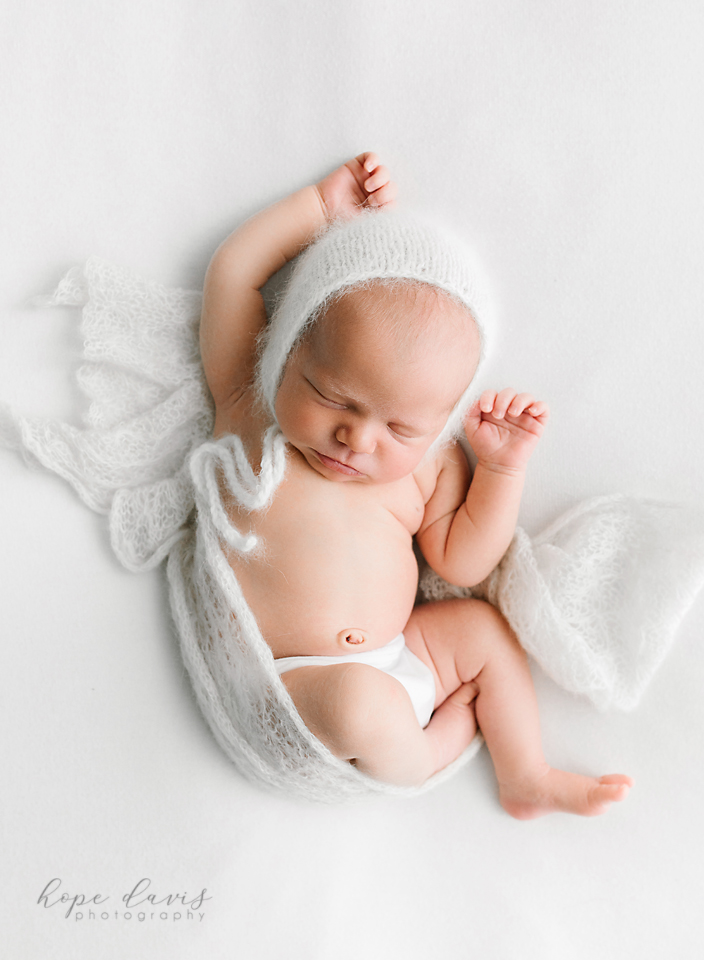 hope davis photography newborn on white blanket unposed with bonnet
