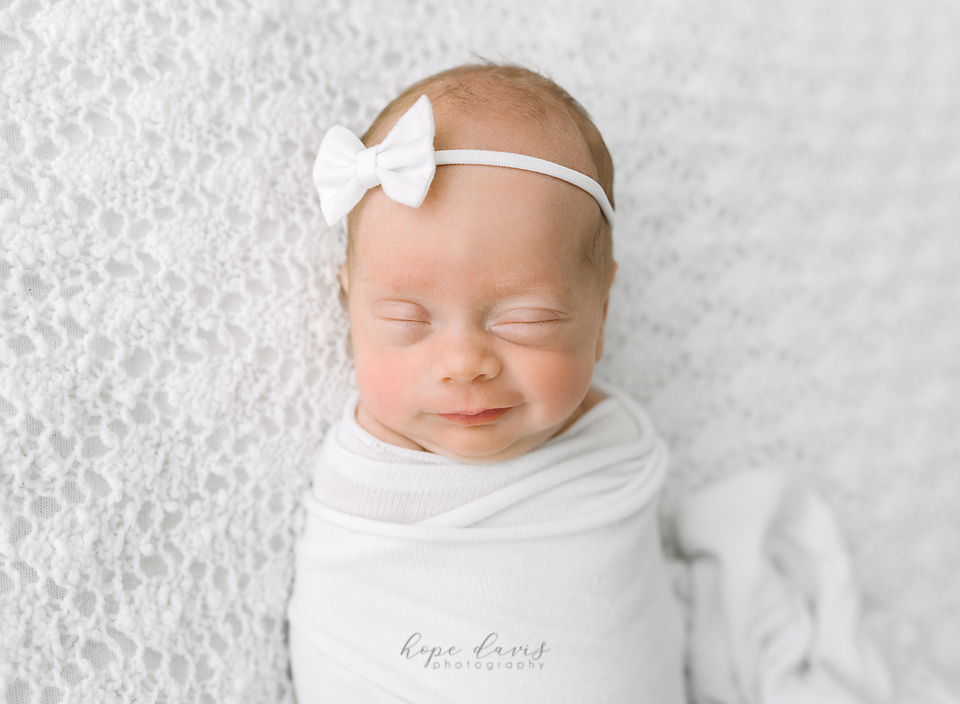 Newborn baby girl on white with simple wrap. Minimalist style newborn photography.